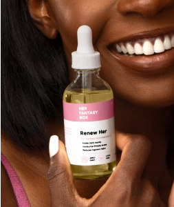 Her Fantasy Box Renew Her face oil held by a smiling woman with glowing skin